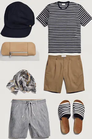 Men's summer clothing with a navy striped shirt, tan shorts, striped swim trunks, a navy cap, a scarf, and slip-on sandals, styled for a relaxed, seaside vacation. These clothing items make the perfect Croatia Travel Outfits.