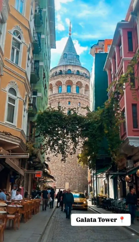 The iconic Galata Tower in Istanbul framed by colorful buildings and a lively street scene below, captured for an Istanbul Instagram story.

