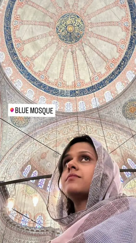 The intricate interior dome of the Blue Mosque with colorful patterns and calligraphy, with me in the frame wearing a haedscarf. A cultural moment captured for an Istanbul Instagram story.