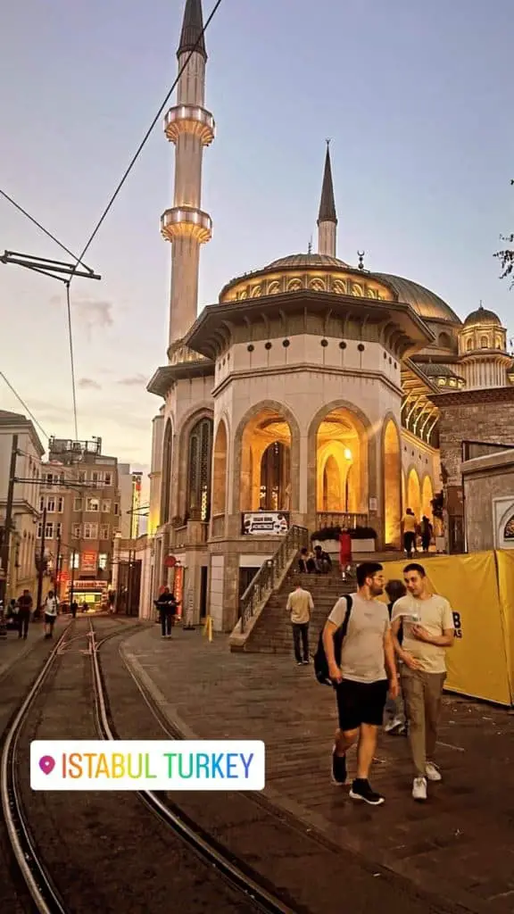 A vibrant mosque in Istanbul captured at dusk, with its glowing architecture and surrounding street bustling with activity. A magical evening scene for an Istanbul Instagram story.