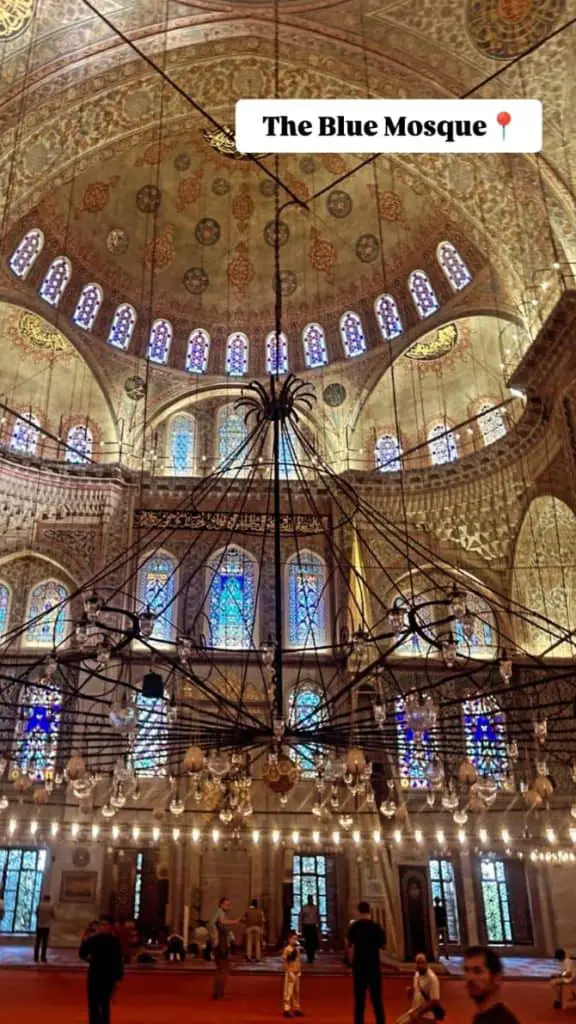  The intricate interior of the Blue Mosque, highlighted by colorful stained glass windows, decorative arches, and glowing chandeliers. A striking cultural moment for an Istanbul Instagram story.