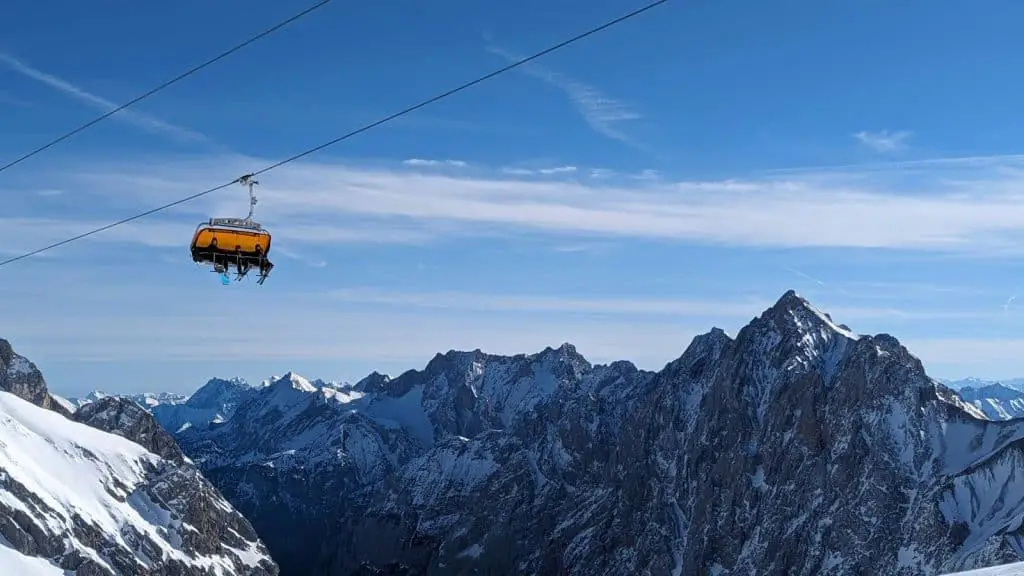 A scenic view of the snow-covered Alps with a cable car ascending towards Zugspitze, Germany’s highest peak. A breathtaking day trip option in a Munich Itinerary 3 Days.