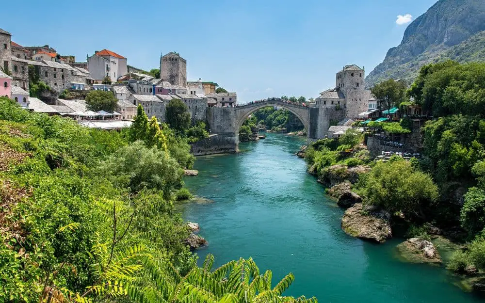 The famous Stari Most (Old Bridge) spanning the emerald-green Neretva River, a stunning highlight for Cheap Travel Destinations in Europe Summer