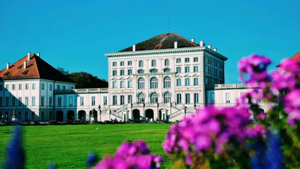 The elegant facade of Nymphenburg Palace, surrounded by lush gardens and blooming flowers. A royal experience to include in a Munich Itinerary 3 Days.