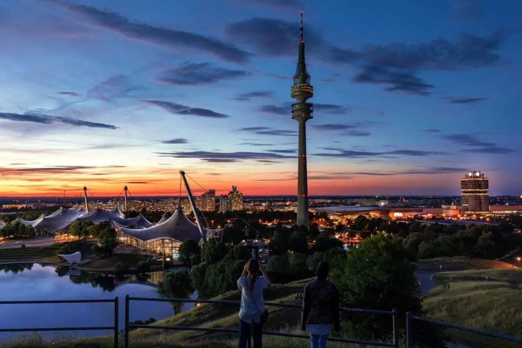 A panoramic view of Munich’s Olympic Park, featuring its iconic stadium and the towering Olympic Tower under a perfect sunset blue sky. A great addition to a Munich Itinerary 3 Days.